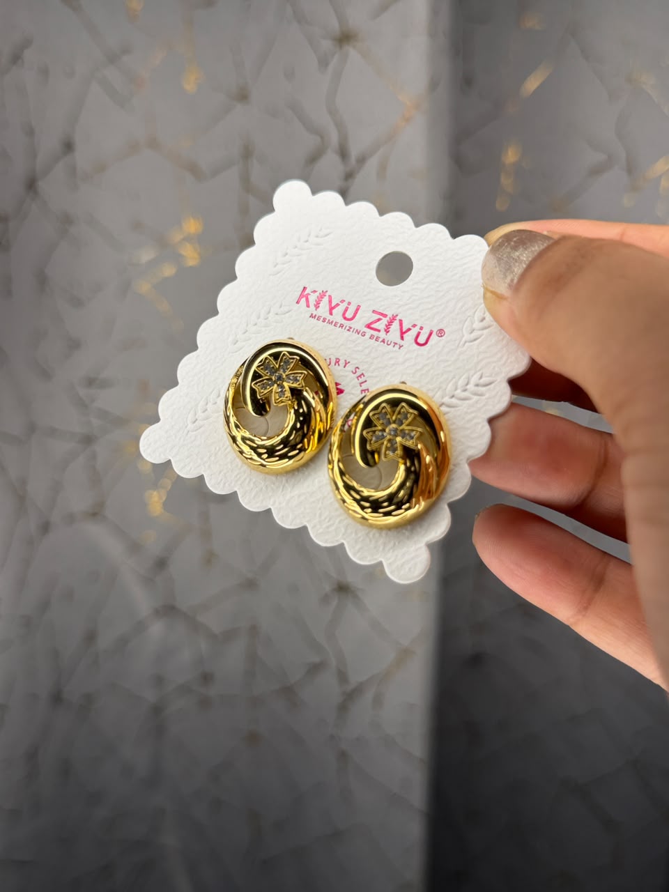 Gold tone sculpted swirl stud earrings with crystal flower detail