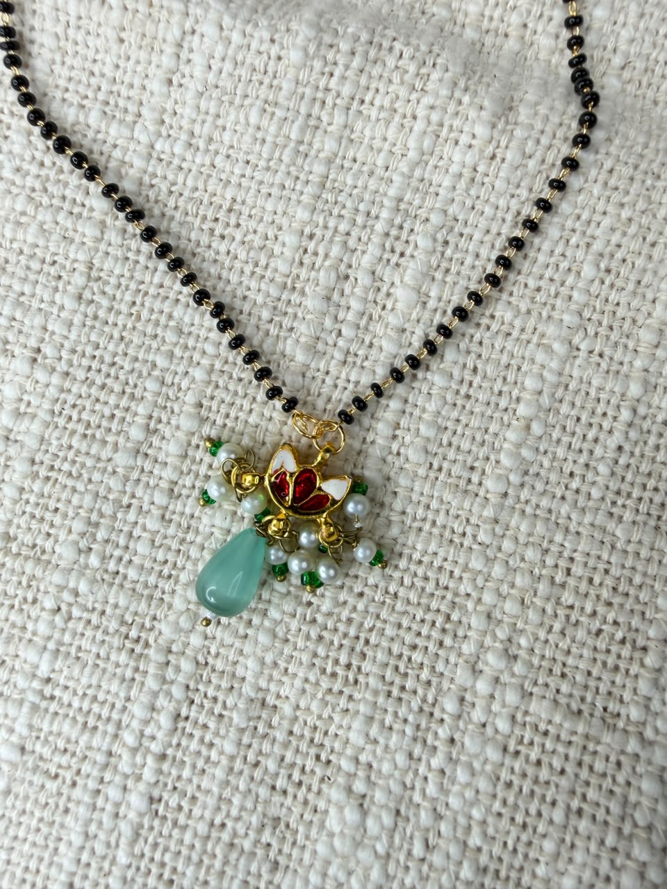 Black bead mangalsutra necklace with lotus motif, pearl cluster and aqua drop pendant