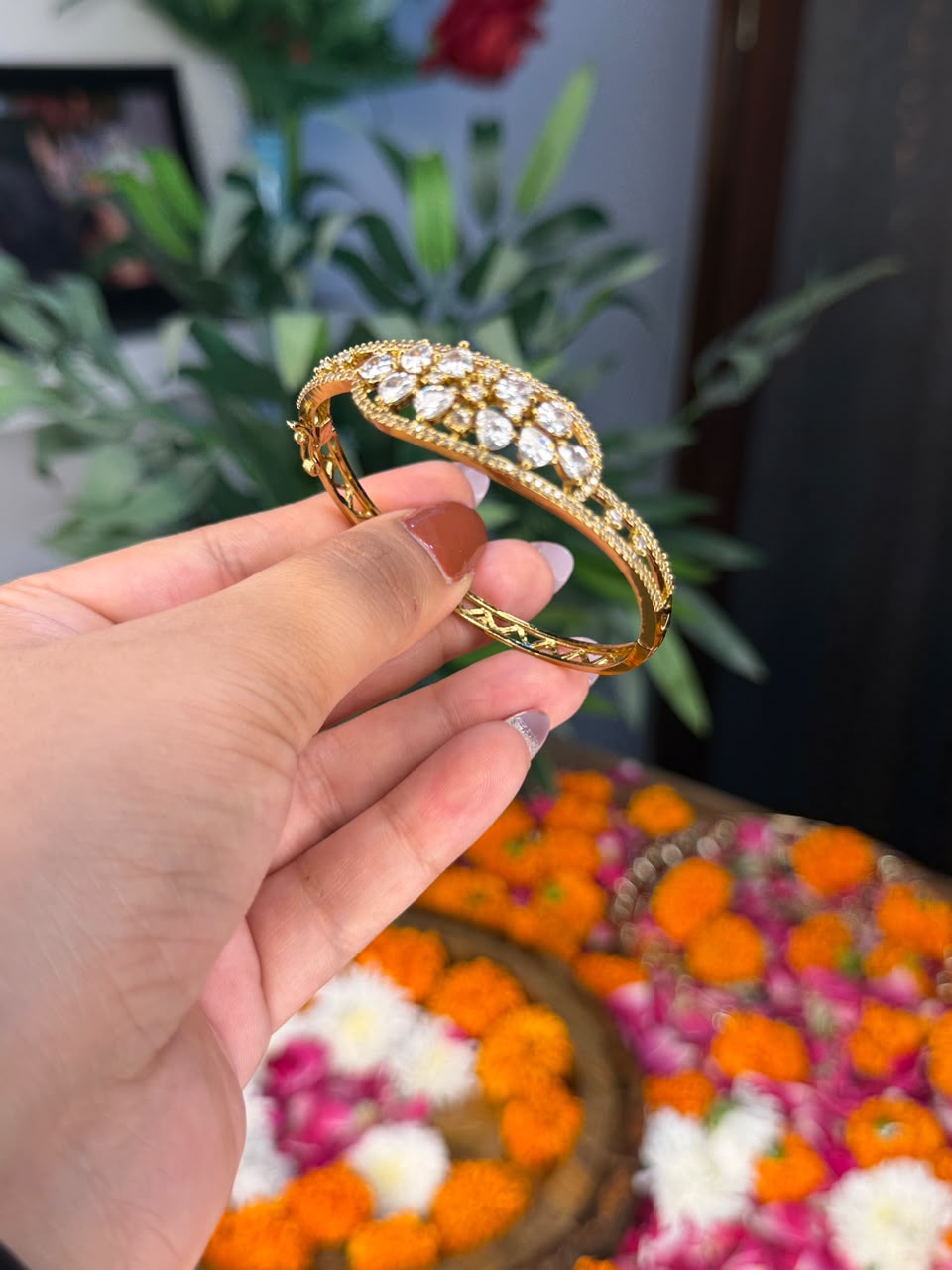 Gold tone hinged bangle with crystal leaf motif