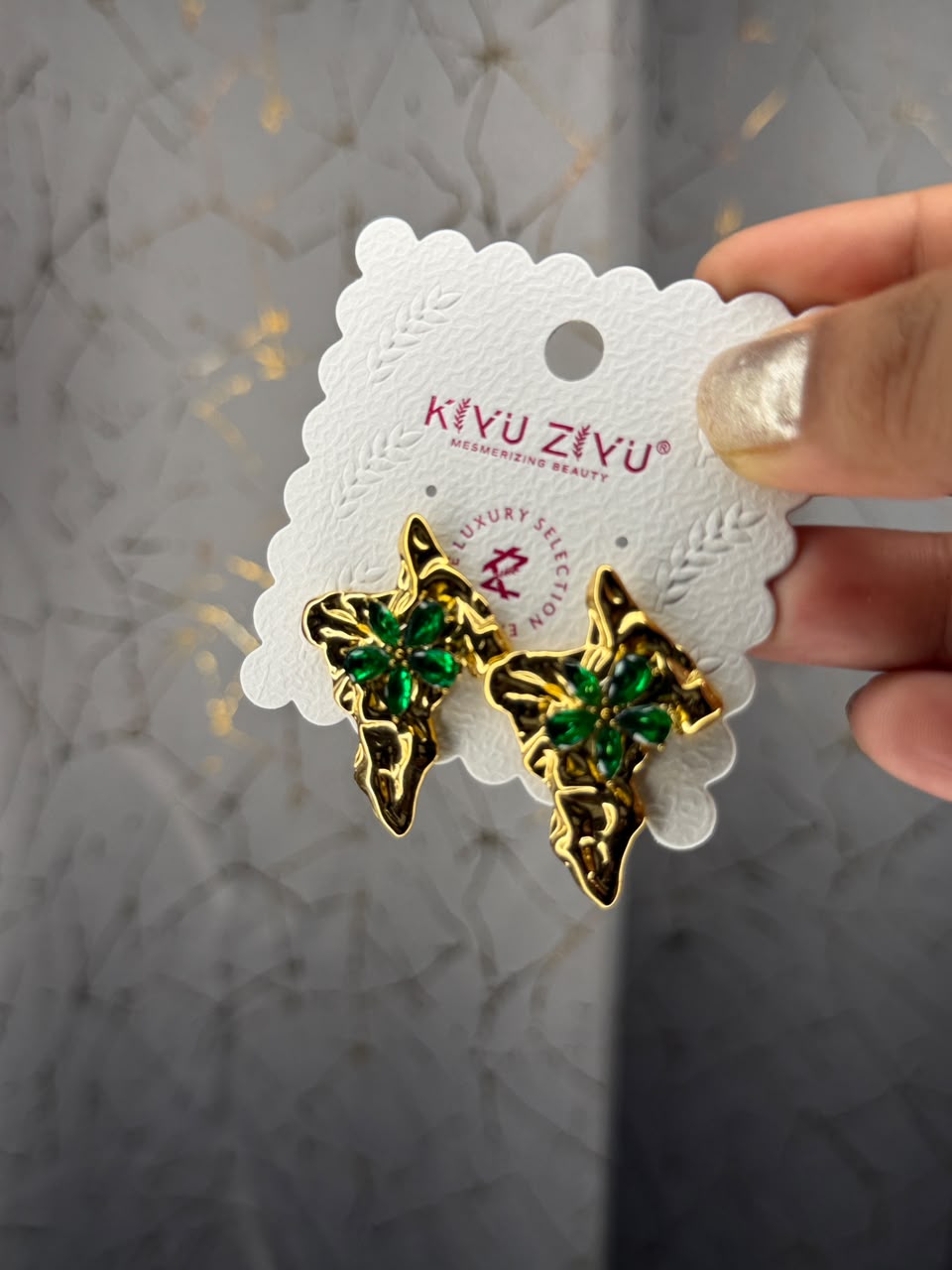 Gold tone sculpted botanical stud earrings with emerald green stones