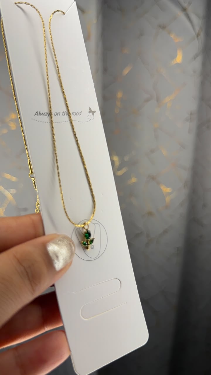 Delicate gold tone chain with tiny emerald green pendant