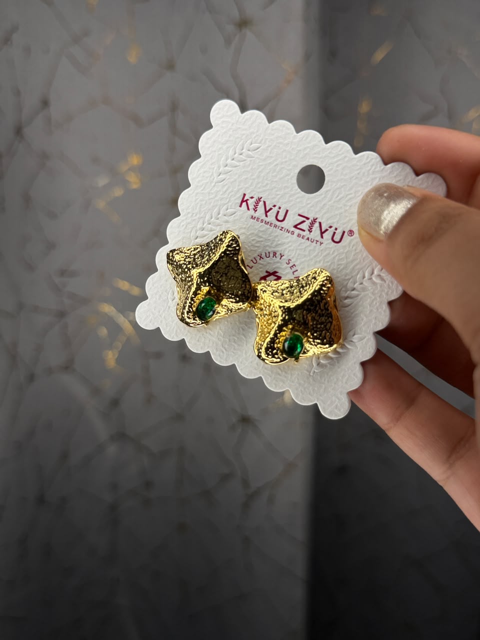 Sculpted gold tone stud earrings with emerald green stone accents