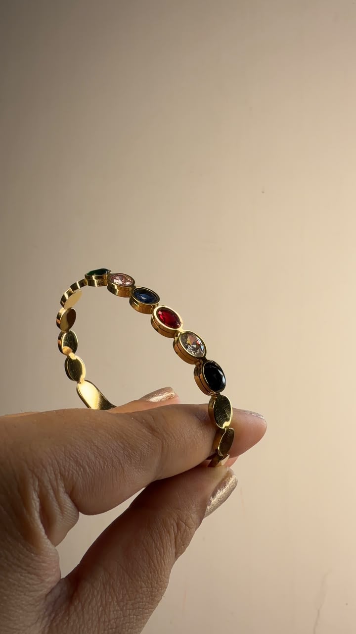 Gold tone bangle bracelet with multicolor oval gemstone accents