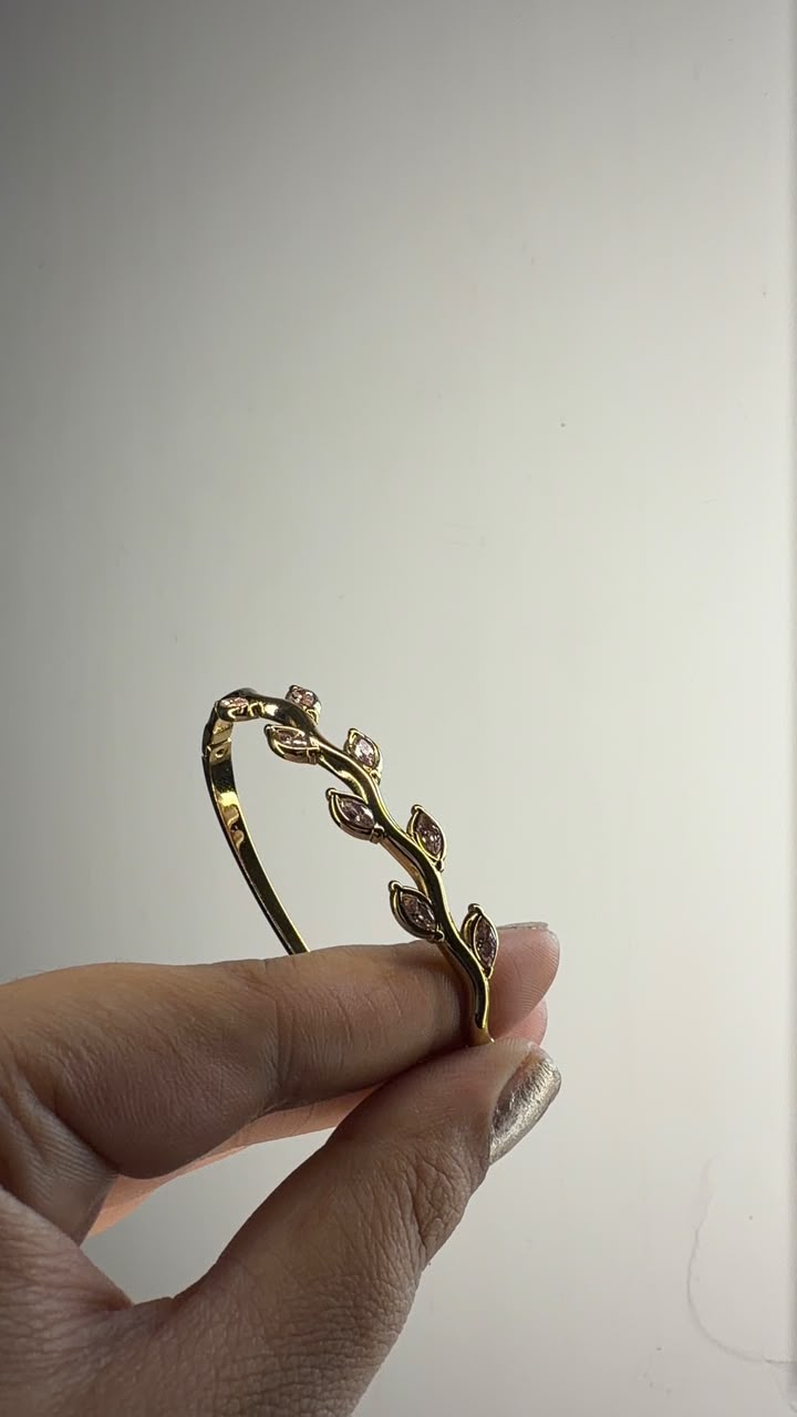Gold tone slim bangle with pink leaf crystal accents