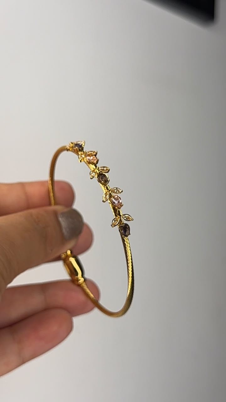 Gold tone bangle with delicate rose and leaf crystal vine detailing