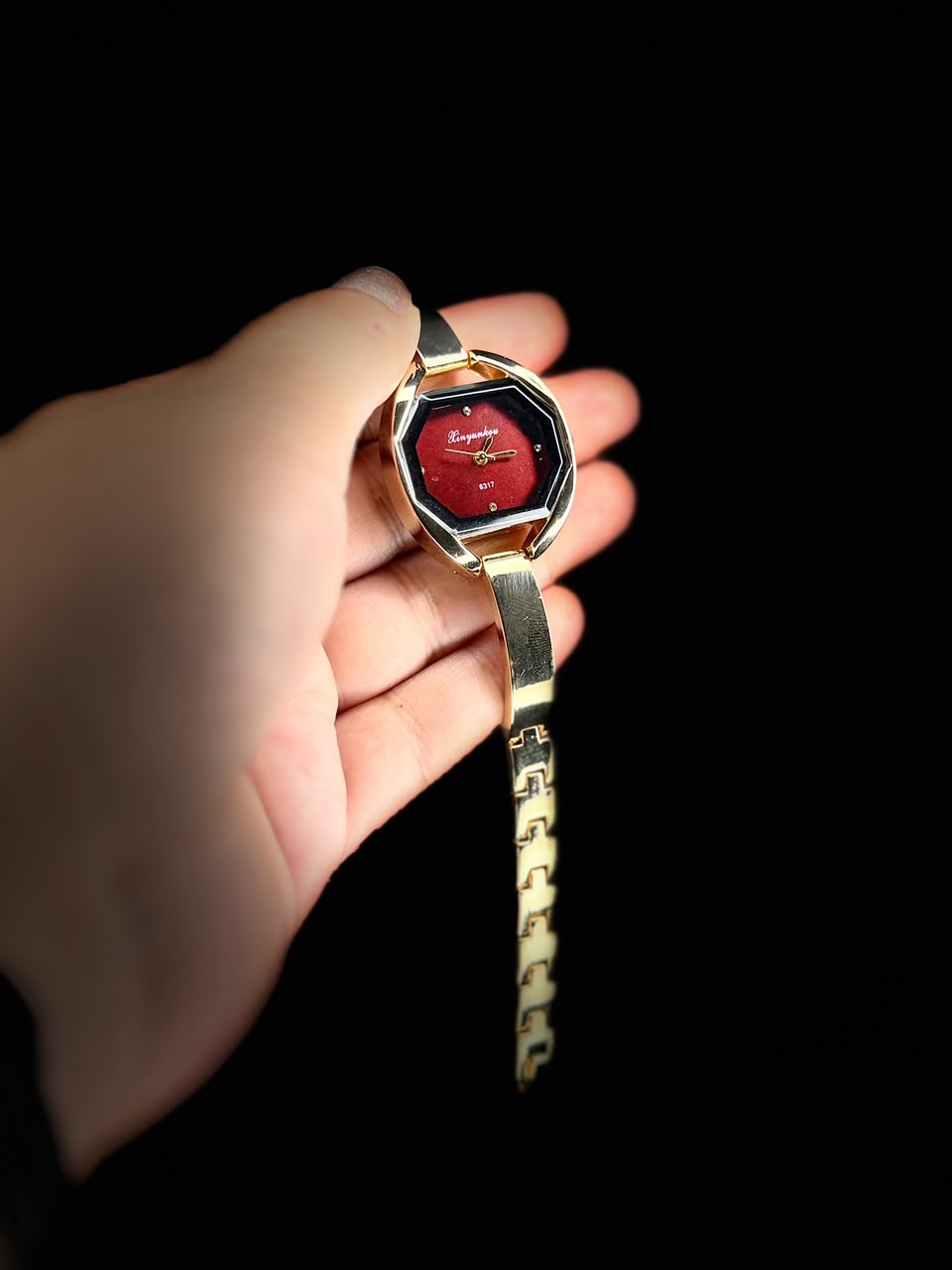 Gold tone wrist watch with deep ruby red dial